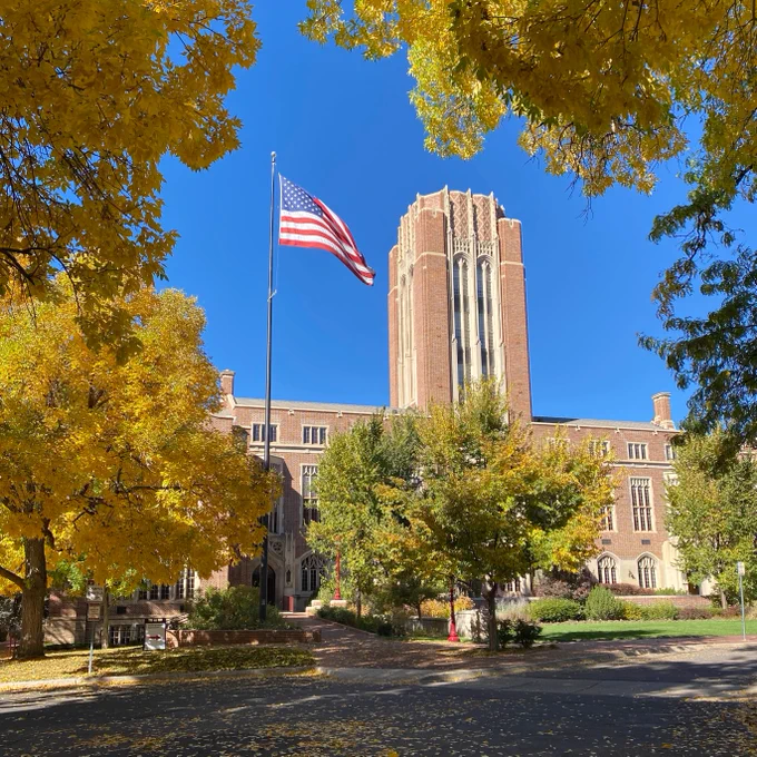 Fall colors on campus featuring the Mary Reed building and the United States flag.