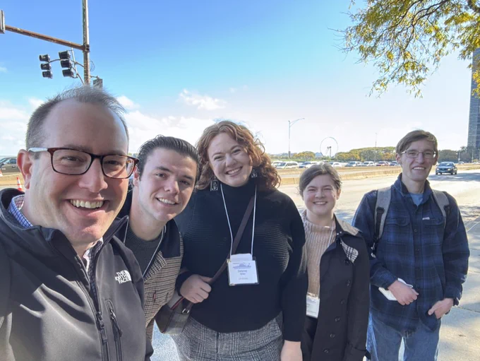 Five happy scientists along Chicago's Lake Shore Drive, with the Navy Pier Ferris Wheel in the background.