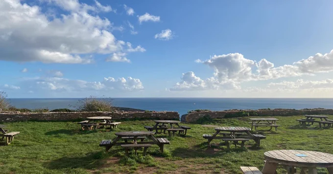 Picture of wooden benches on Berry Head cliff top looking out to blue sea. 