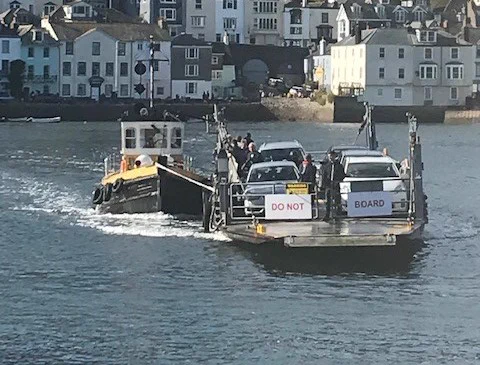 a car ferry on the water with houses in the background