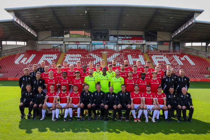 A group shot of the Wrexham AFC squad and staff in front of the Macron Stand.