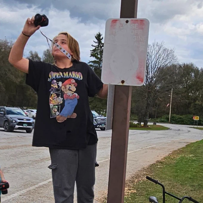Image of youth taking a photo with a camera.