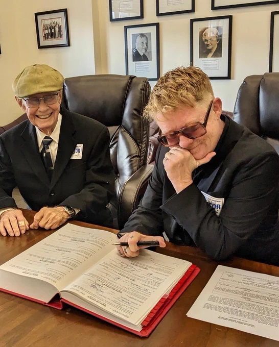 Kelly Besser, seated with her father, signing the Oath Book at the Los Angeles City Clerk's Office in City Hall, Oct. 12, 2023.