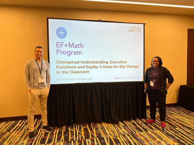 Two members of the EF Math team standing in front of a projector screen with the title of their session: Conceptual Understanding, Executive Functions and Equity: 3 areas for Big Change in the Classroom.