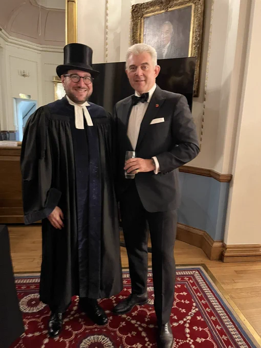 Rabbi Morris and Brandon Lewis standing together. Rabbi Lewis is wearing a gown, Geneva preaching bands and a top hat.