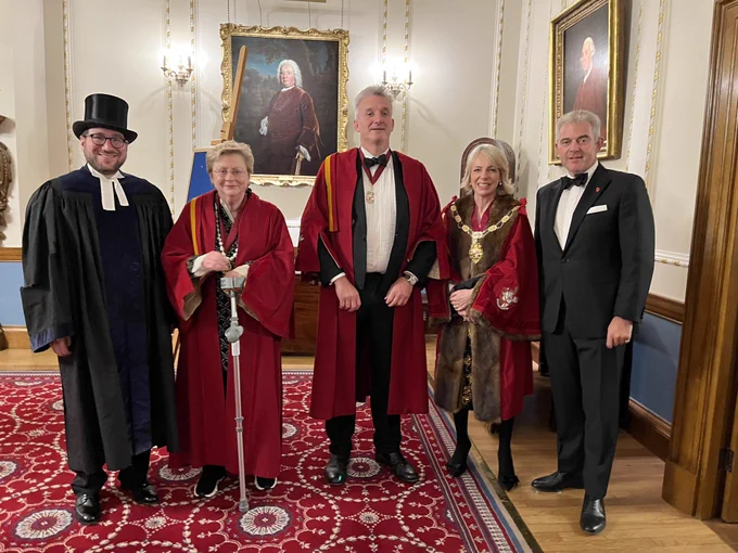 The Master and wardens of the Company, wearing red gowns between Rabbi Morris and Brandon Lewis.