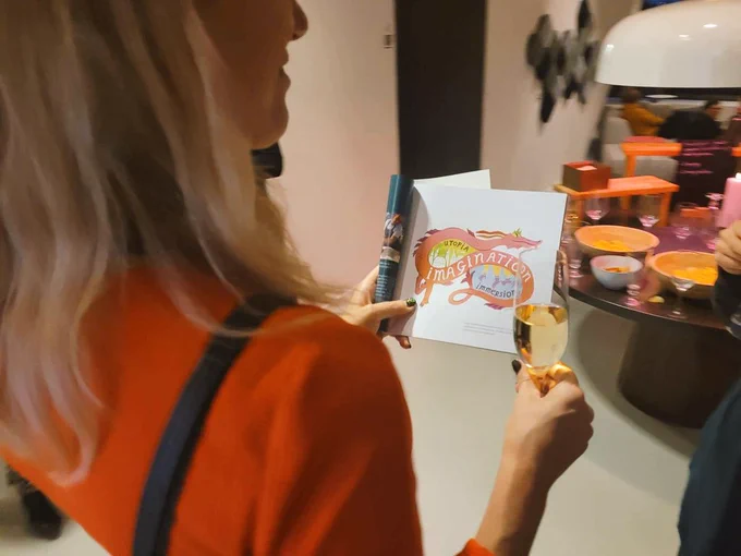 Marianne holder et trykt program, der viser en illustration af en drage. 