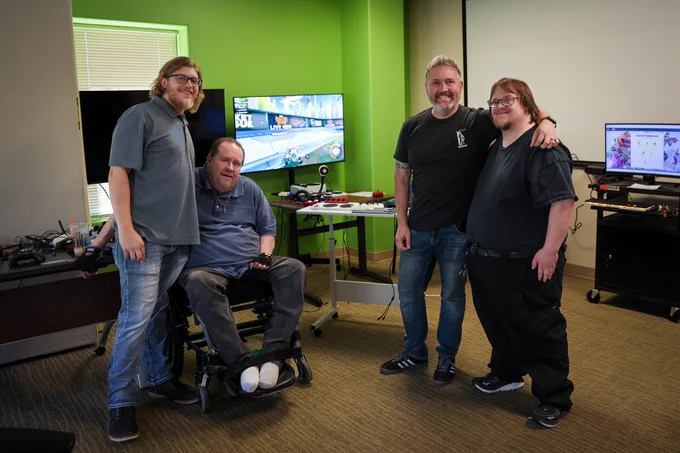 Erik Johnson standing with members of the independent center in front of adaptive gaming equipment.