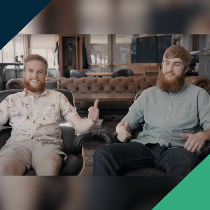 Two brothers smiling as they sit next to each other.
