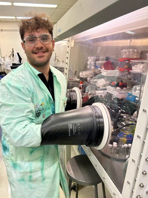 Justin Shmordok with his hand inside of a glovebox, using Schlenk techniques to create new compounds.