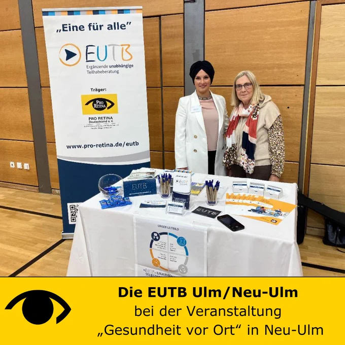Links Frau Debreli (EUTB-Beraterin) rechts Frau Koch (stellvertretende Oberbürgermeisterin Neu-Ulm) stehen vor dem Stand der EUTB auf dem verschiedene Informationsmaterialien ausliegen. Unter dem Foto ist ein gelber Balken mit dem Logo der PRO RETINA und daneben steht: Die EUTB Ulm/Neu-Ulm, bei der Veranstaltung „Gesundheit vor Ort“ in Neu-Ulm
