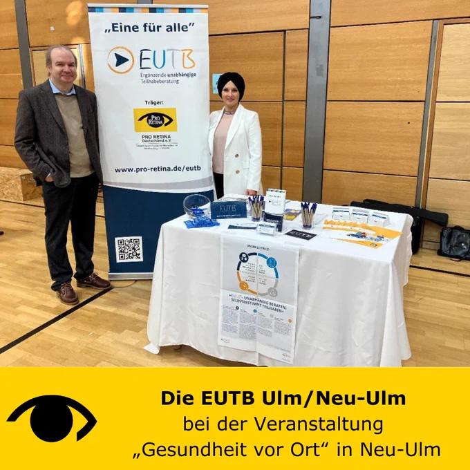 Herr Löchner (Leiter Gesundheitsmanagement Neu-Ulm) und rechts Frau Debreli (EUTB-Beraterin). Zwischen den beiden ist ein RollUp der EUTB und davor  steht der Stand der EUTB auf dem verschiedene Informationsmaterialien ausliegen. Unter dem Foto ist ein gelber Balken mit dem Logo der PRO RETINA und daneben steht: Die EUTB Ulm/Neu-Ulm, bei der Veranstaltung „Gesundheit vor Ort“ in Neu-Ulm