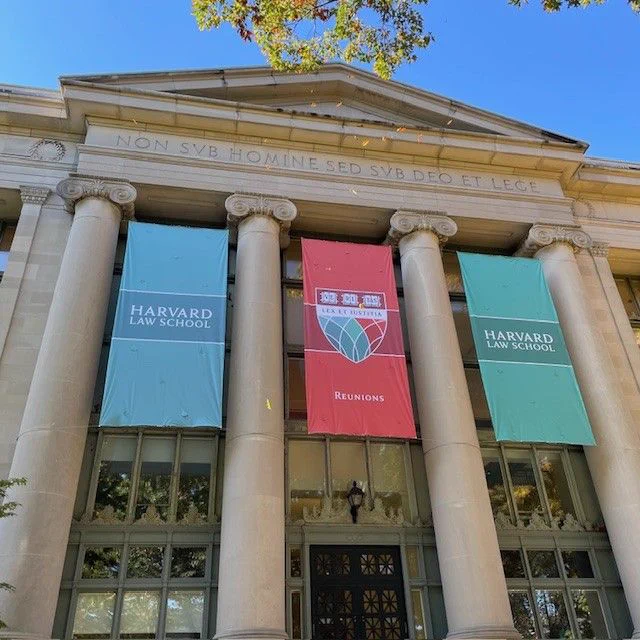 The entrance to Langdell Hall, with four columns and three banners displayed over the door. The banners say "Harvard Law School" and "Reunions."
