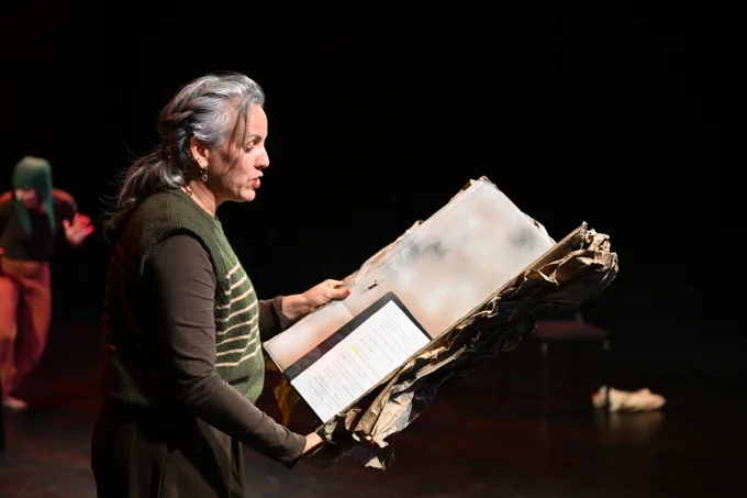 A woman reads from a gigantic, ancient-looking storybook. 
