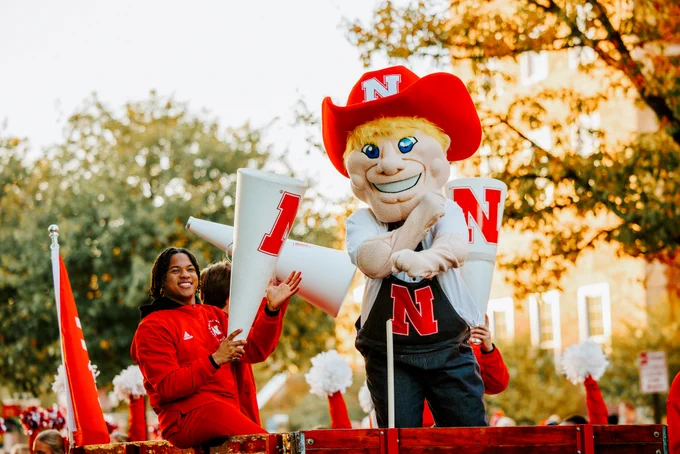 Husker Cheerleader Amani and Herbie Husker ride in the homecoming parade