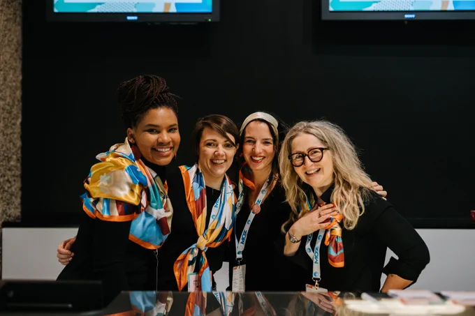 Four women posing for a picture with colourful scarves