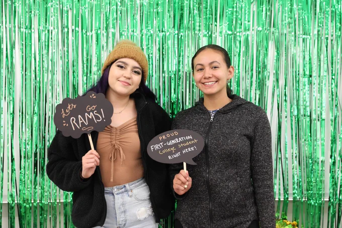 Students hold up first generation photobooth props and pose in front of a green background