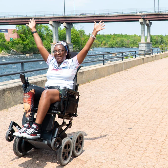 Women with hands raised riding her iBOT wheelchair