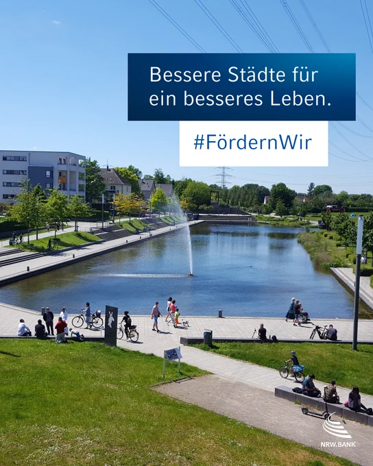 Eine Parkanlage mit Wasserbecken und Grünflächen bei blauem Himmel und Sonnenschein. Spaziergänger und Fahrradfahrer, Menschen sitzen auf Bänken.