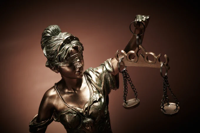 Photo of a statue of Lady Justice with brown background.