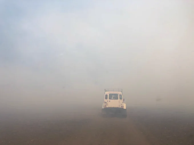 Field vehicle disappearing into smoke from lava-ignited wildfires