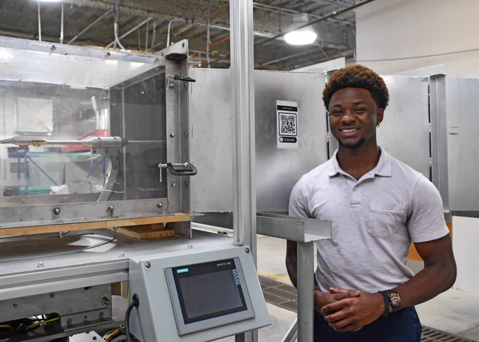 Dean Gerald stands in front of a wind tunnel located in one of the CEC mechanical engineering labs. It is dedicated to producing an airstream of a known velocity past models of solid objects to investigate flow or the effect of wind on the full-size object. 