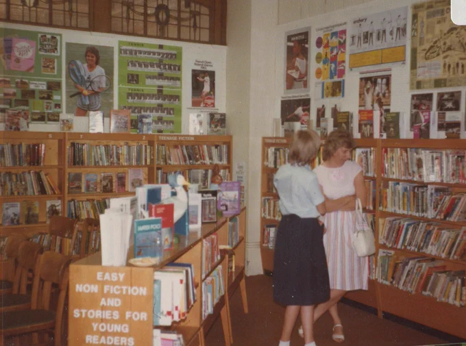 Two ladies look at books in the children's section