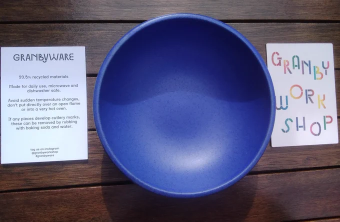Background is a dark wood table,  outside in the sun. Central is large, shallow matt cobalt blue bowl. On either side are the cards that came with . One says: GRANBY WORK SHOP in multicolour. The other says: GranbywRe 99.98% recycled materials. Made for daily use, microwave and dishwasher safe. Avoid sudden temperature changes,  don't put directly over an open flame or into a very hot oven.  If any pieces develop cutlery marks, these can be removed by rubbing with baking soda and water.