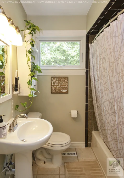 Pleasant bathroom with new awning window we installed. This charming little bathroom looks great with this new white window against beige walls and amongst white fixtures and brown and black tile. Find out more about replacing the windows in your home from Renewal by Andersen New Jersey, New York City, Staten Island and The Bronx.