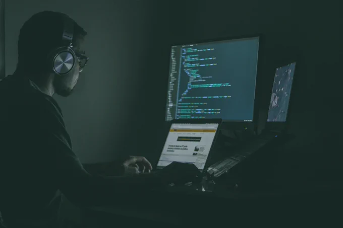 Man in a dark room coding. 