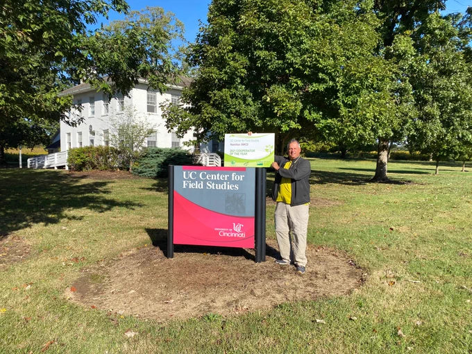 Dr. Ken Petren displaying the award next to the Field Center's welcome sign