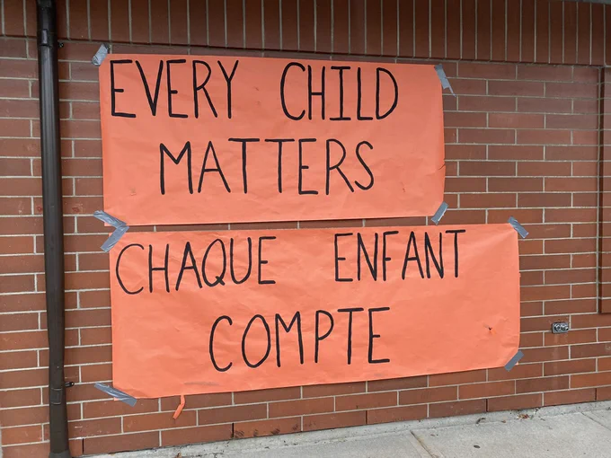 Two banners on orange paper: Every Child Matters and Chaque Enfant Compte.