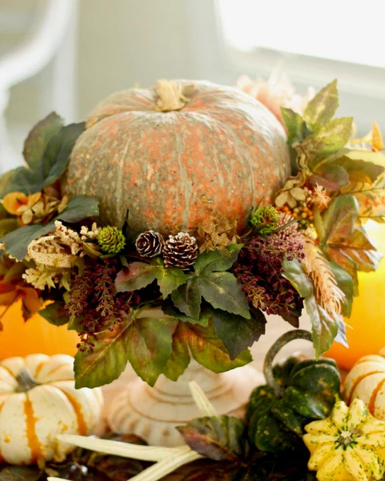 A pumpkin surrounded by a wreath of leaves and placed on a pedestal. 