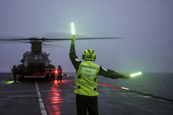 An RAF Chinook lands on HMS Albion at dusk