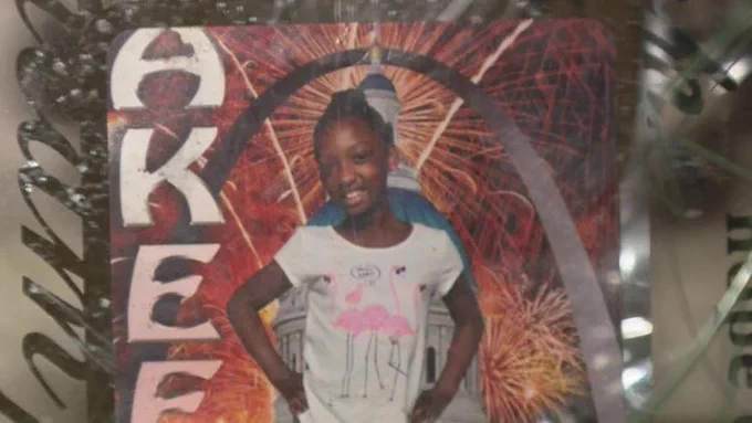 Picture of Akeela Jackson, smiling standing in front of a photo of the arch.