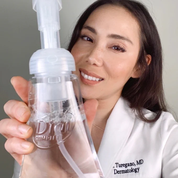 Dr. Mamina holds up Dial Clean   Gentle Foaming Hand Wash and smiles