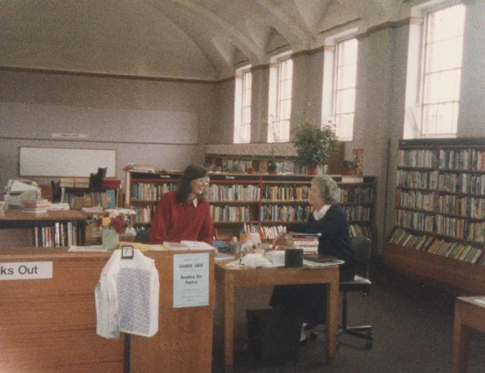 An old photo of the interior of Cheriton Library. Librarians at the front desk.