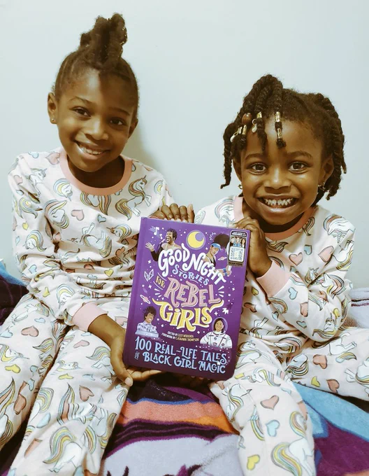Two little Black girls in matching pink unicorn pj's holding up their new book