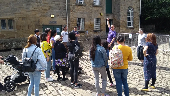 A crowd of people listen to a staff member at Barnsley Museum