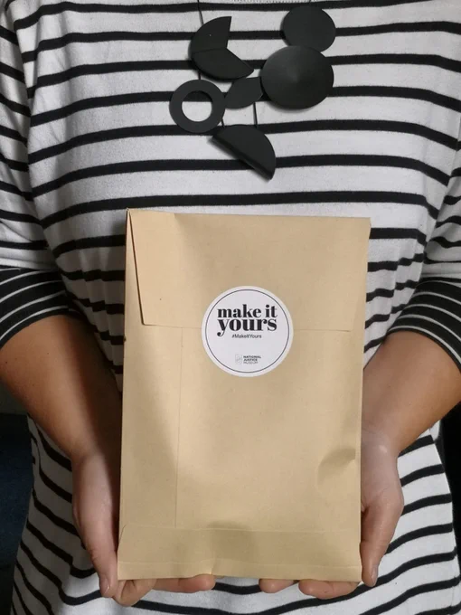 A person holds a 'Make it Yours' workshop in a brown envelope