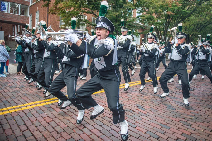 Marching 110 band member jumps in the air during the 2019 Homecoming Parade.