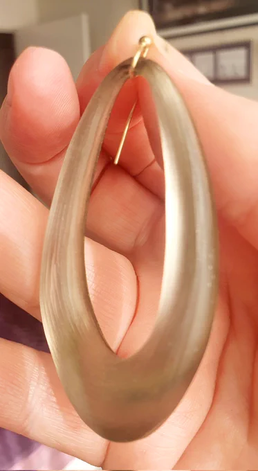 A gold coloured oval ring earring with a small gold hook.
