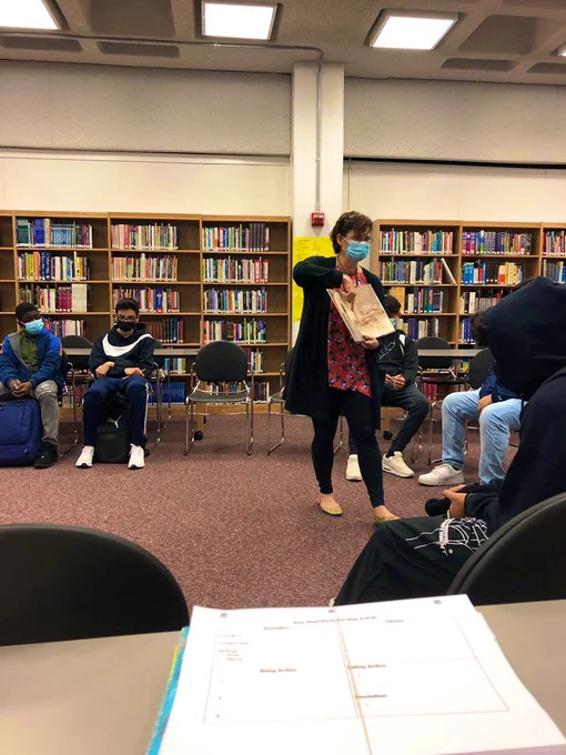 Librarian Mrs. Barbuzza reads a book and displays illustrations to students.