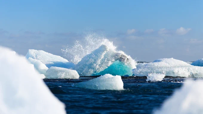Image of a wave crashing over an iceberg