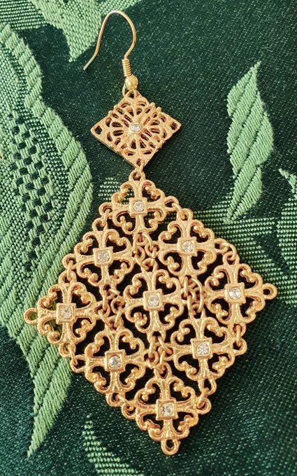 A long gold earring made of 2 diamonds, a,small one on top, and a large one on the bottom. Each diamond has several sparkly stones mounted on it.