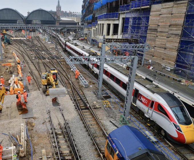 An elevated view of London Kings Cross station, taken in Spring 2021, with engineers working to the left, replacing track and components as part of the major Kings Cross Remodelling project, whilst an LNER and Great Northern train pass to the right hand side.