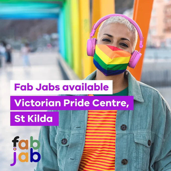 A woman of colour with short blond hair wearing a rainbow mask. They are listening to music with overhead headphones that are pink in colour. There is text on the image that say’s “Fab Jabs available Victorian Pride Centre, St Kilda”. There is also a Fab Jab logo that has the colours black, brown, green, purple, orange, and blue, the dot over the letter J has the colour yellow with a ring in purple colour to acknowledge the Intersex community. The person in the image is also wear a blue corduroy jacket and a yellow and red horizontal stripe shirt.