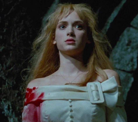 From Edward Scissorhands she stands outside in the dark with blood on the side of her white dress and a blank look on her face.