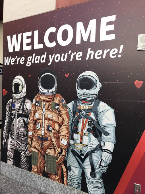 All Things Open signage says: “Welcome. We’re glad you’re here!” Below, a depiction of three astronauts.