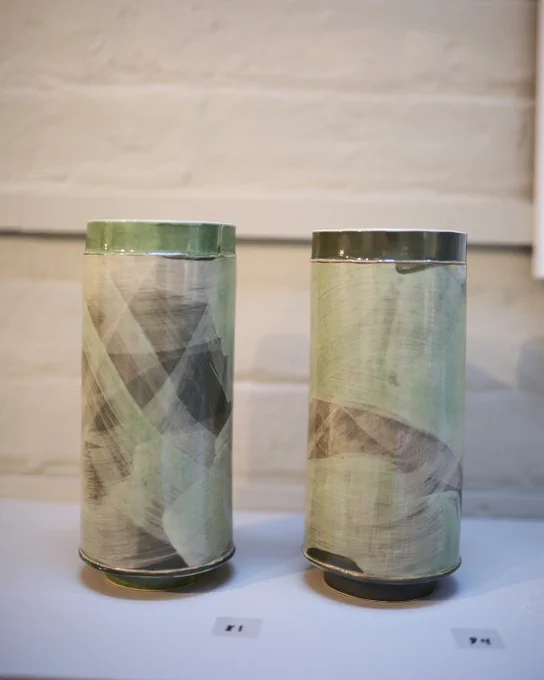 Close up of ceramic vessels with muted, green tones and abstract pattern.